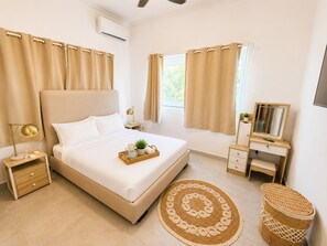 A modern bedroom with a bed, bedside table, lamp, dresser, mirror, and a woven rug. - 3bd with rooftop ocean view in Sosua Ocean Village (Sosúa)
