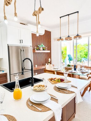 A modern kitchen with a central island, stainless steel appliances, and a dining area with a view. - 3bd with rooftop ocean view in Sosua Ocean Village (Sosúa)