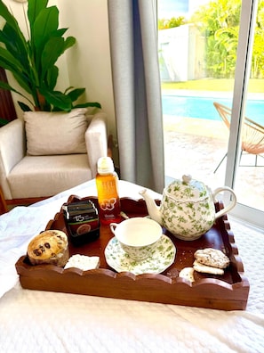 A tray with a teapot, cup, cookies, and a bottle on a bed. - 3bd with rooftop ocean view in Sosua Ocean Village (Sosúa)