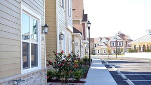 A row of townhouses with a paved driveway and a small garden with red flowers. - 4BR Townhome 15min to Disney (Kissimmee)