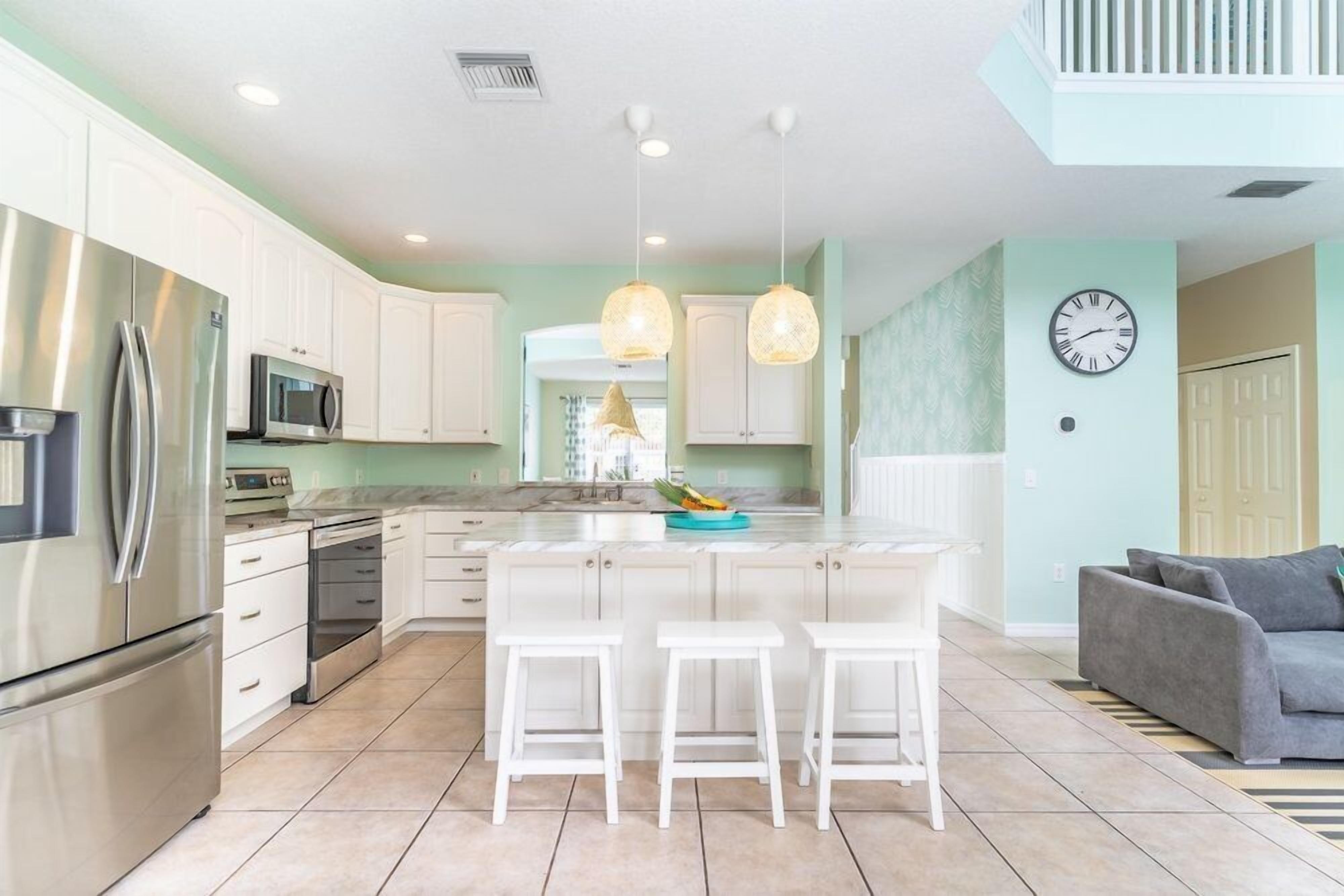 A modern kitchen with white cabinets, stainless steel appliances, and a central island with stools.