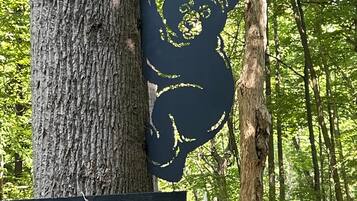Un árbol con el silueta tallada de un oso y una pizarra con el letrero 'ARLIRES WELCOME'.