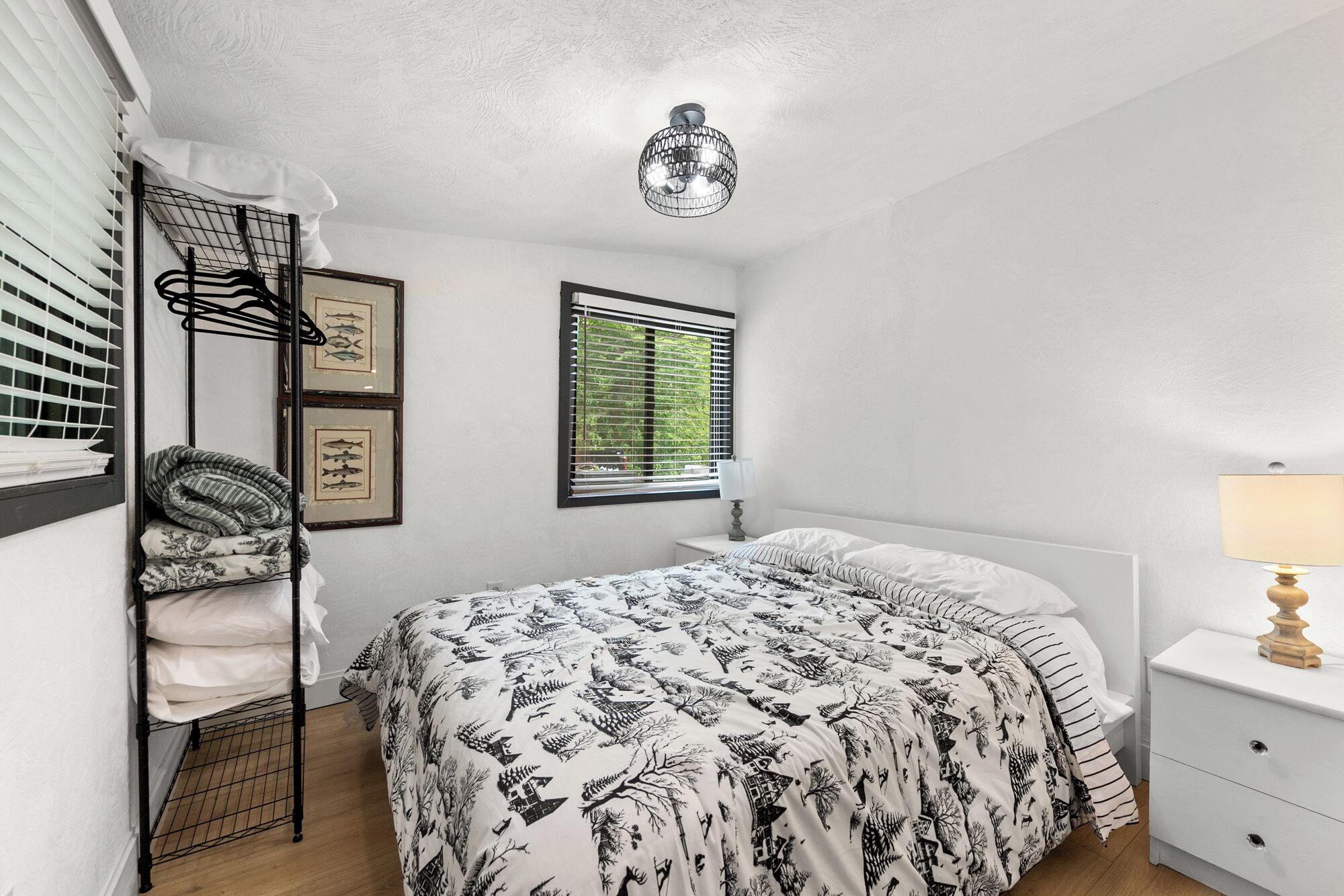 Un dormitorio con una litera, una cama con cubrecama estampado, una lámpara de noche y cuadros de peces en la pared.