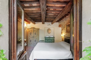 A bedroom with a wooden ceiling, a bed, a dresser, and a mirror. - Orcio – Romantic studio with private terrace near the pool (Reggello)