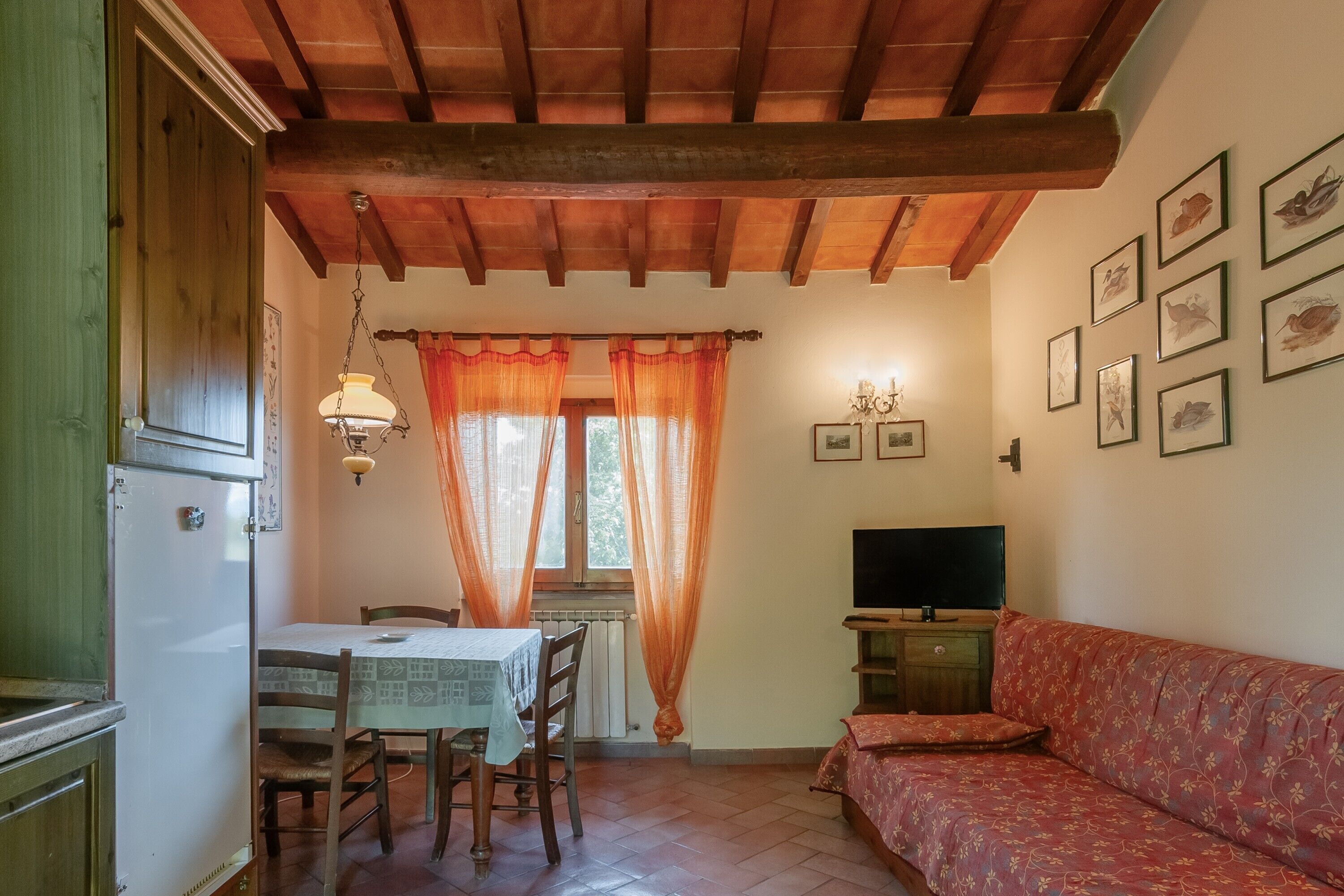 Una stanza con un tavolo da pranzo, sedie, un divano, una televisione e quadri appesi al muro.