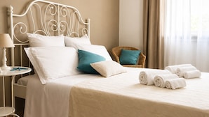 A neatly made bed with pillows, a bedside table with a lamp, a chair, and rolled towels on the floor. - La Casa Più Bella | Near San Vito Lo Capo, Cornino & Monte Cofano (Custonaci)