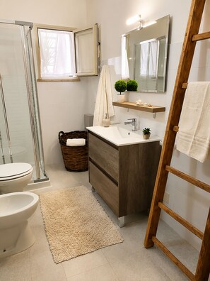 Un baño con ducha, inodoro, lavamanos y una escalera de madera.
