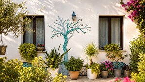 A courtyard with a mosaic tree, potted plants, and a wall-mounted lantern. - La Casa Più Bella | Near San Vito Lo Capo, Cornino & Monte Cofano (Custonaci)