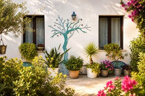 A courtyard with a mosaic tree, potted plants, and a wall-mounted lantern. - La Casa Più Bella | Near San Vito Lo Capo, Cornino & Monte Cofano (Custonaci)