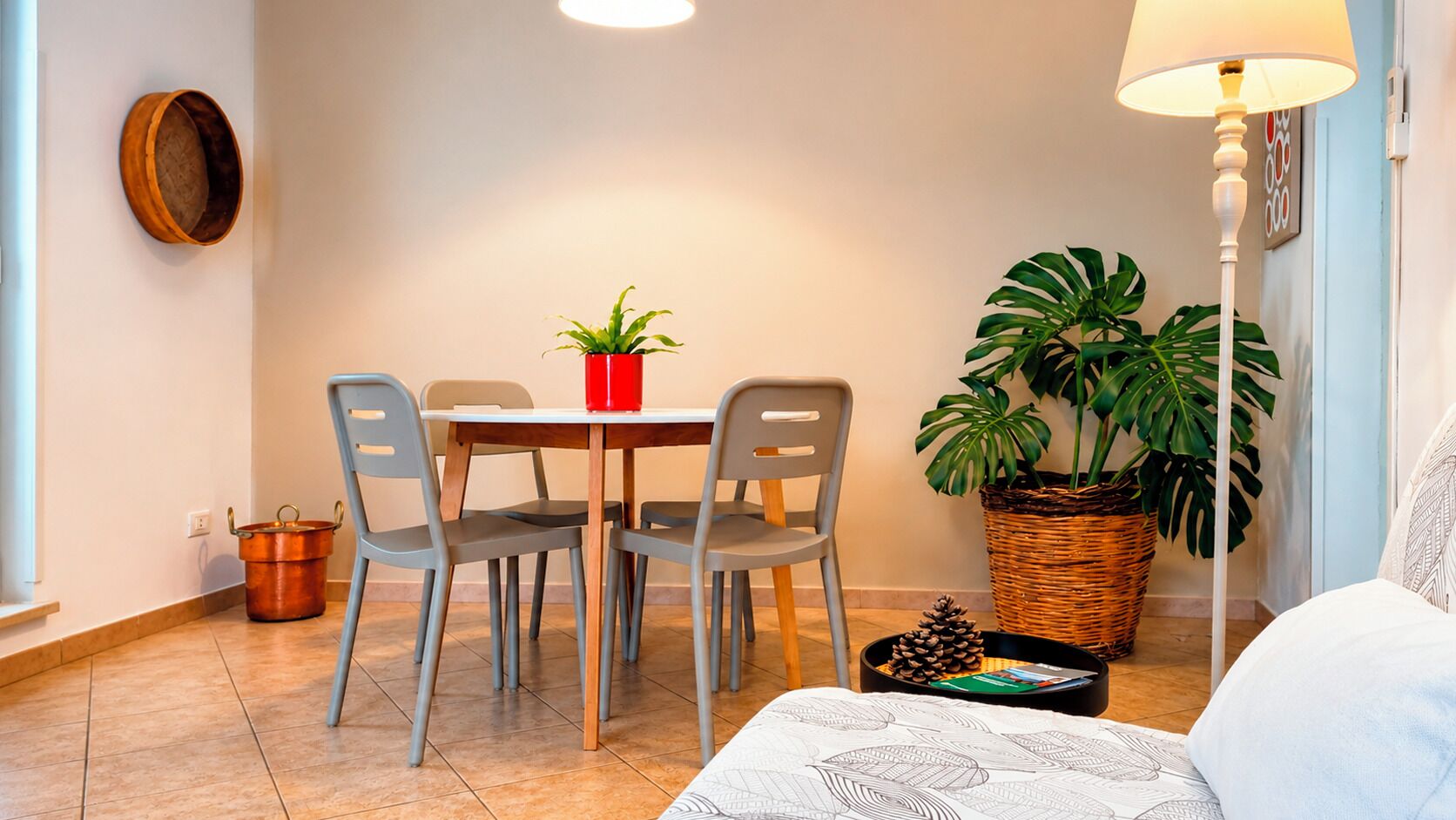 A dining area with a table, chairs, a red pot, and a potted plant.