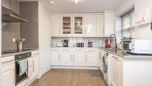 Una cocina moderna con armarios blancos, horno empotrado, lavadora y microondas.