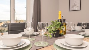 Una mesa de comedor dispuesta con cuencos blancos, copas de vino y una botella de champán.