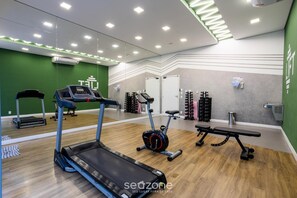 Un gimnasio con cintas de correr, elíptica y un banco.