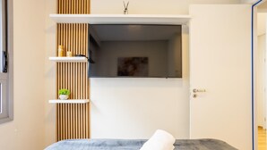 A modern bedroom with a bed, a small shelf with toiletries, a potted plant, and a door leading to another room. - Stay Steps fr/ the Metro and Ibirapuera Mall in Indianopolis - Noes (São Paulo)
