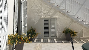 A white building with a staircase leading to an upper level. There are potted plants with yellow flowers at the base of the stairs. - VILLA LA SCIROCCATA LEUCA (Santa Maria di Leuca)