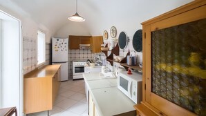 A kitchen with white appliances, wooden cabinets, and a tiled backsplash. - VILLA LA SCIROCCATA LEUCA (Santa Maria di Leuca)