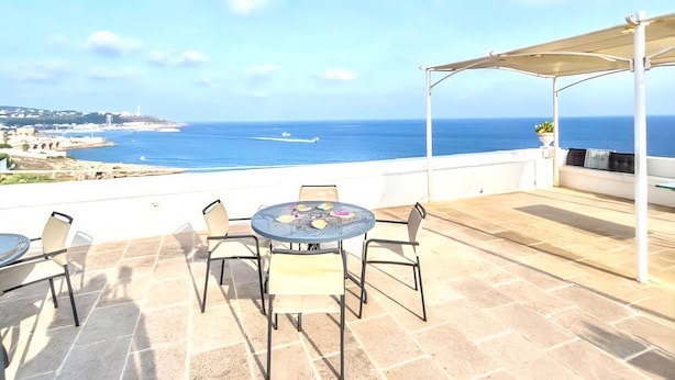 A terrace with a table and chairs overlooking a coastal view. - VILLA LA SCIROCCATA LEUCA (Santa Maria di Leuca)