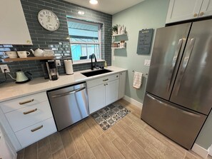 A kitchen with a stainless steel refrigerator, a dishwasher, a sink, and a clock on the wall. - COCO BUNGALOW - All new w/ heated pool, bikes, beach equipment & more (Englewood)