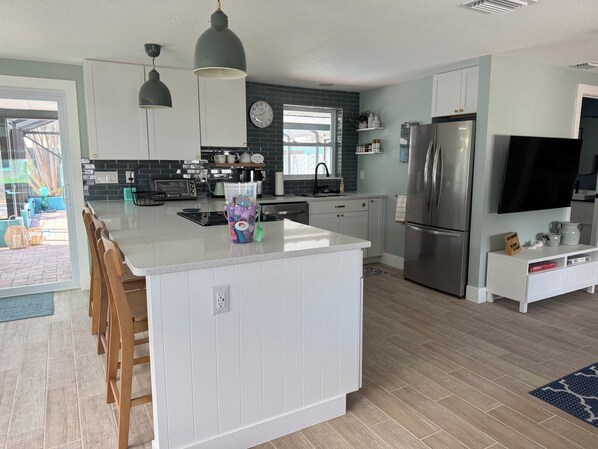 A modern kitchen with a central island, stainless steel appliances, and a dining area with wooden chairs.