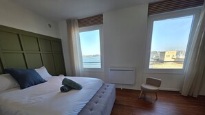 A hotel room with a large bed, a chair, and a view of the sea. - Comfortable apartment with an incredible sea view (Landéda)