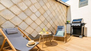 A sunlit outdoor area with two lounge chairs, a small table with drinks, and a barbecue grill. - Comfortable apartment with an incredible sea view (Landéda)