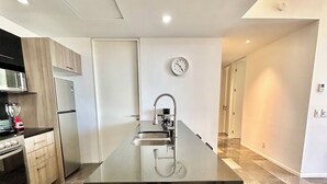 A modern kitchen with a central island, stainless steel appliances, and a minimalist design. - El DePA, Luxury and Comfort, resort-like amenities (Zapopan)