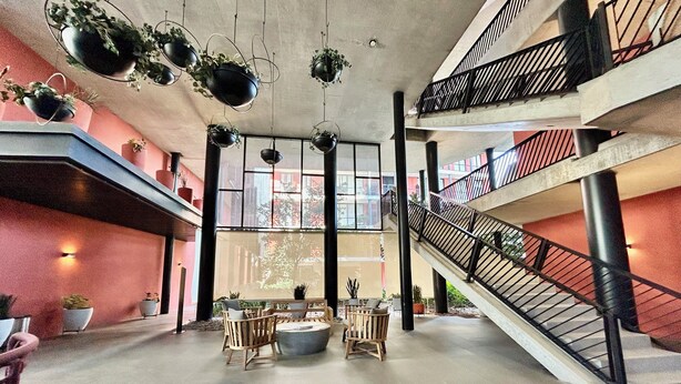 A spacious atrium with a central seating area, multiple hanging planters, and a staircase. - El DePA, Luxury and Comfort, resort-like amenities (Zapopan)