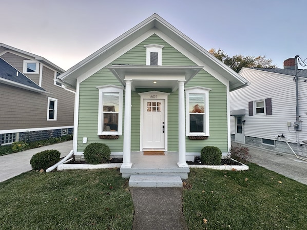A single-story house with a front porch, a door labeled "601", and a small front yard with trimmed bushes.