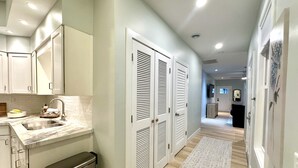 A modern kitchen with white cabinets, a stainless steel sink, and a built-in trash can. - Cozy Cottage Retreat • 5 Min to Cedar Point • Deck + Screened Patio (Sandusky)
