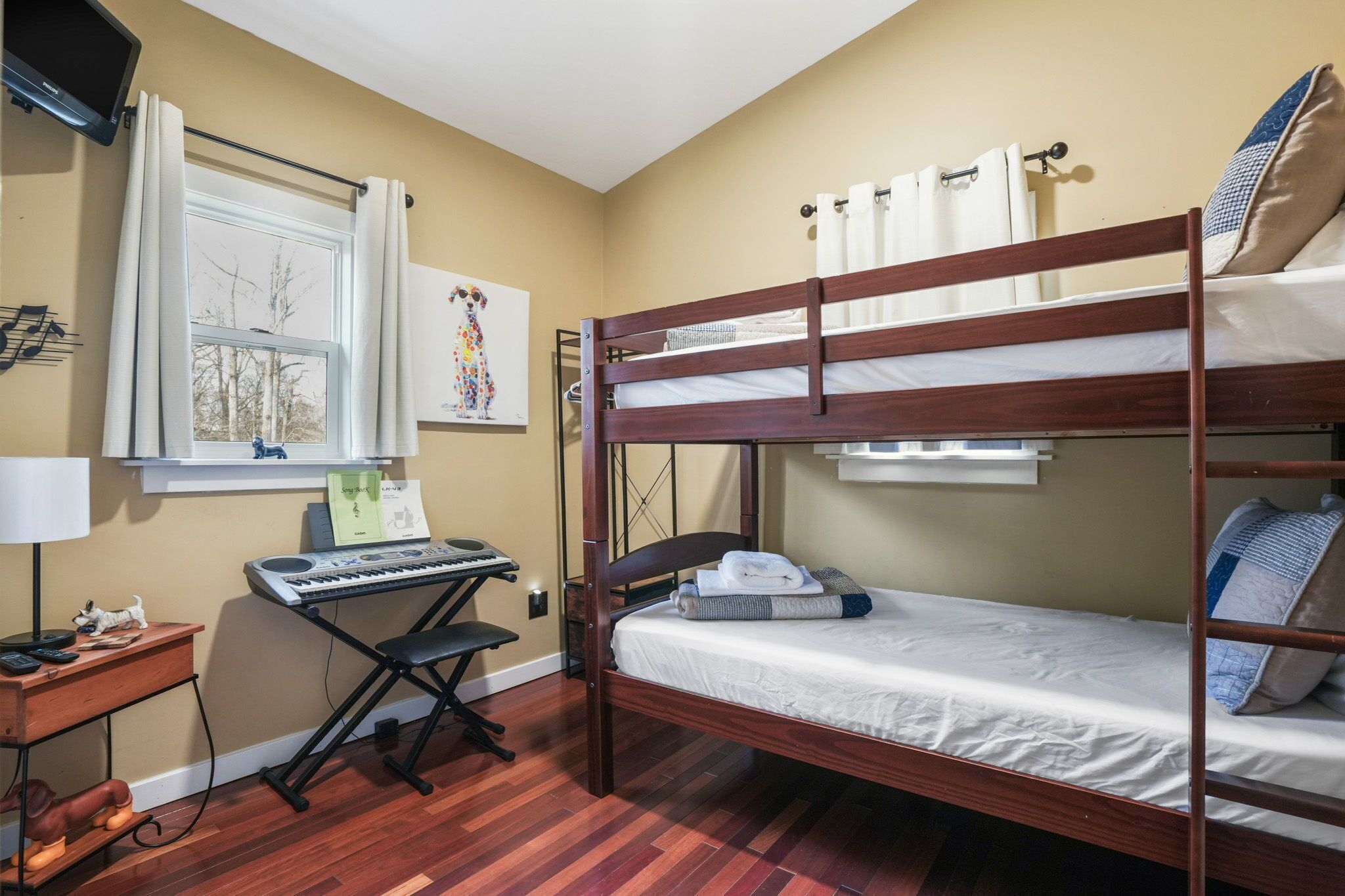 A bunk bed room with a desk, keyboard, and lamp.
