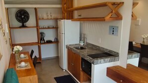 A compact kitchen with a built-in stove, a sink, and wooden cabinets. - Chalet with private garden, ideal for couples and families with children. (São Miguel do Gostoso)