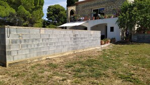 A stone building with a white facade, a covered patio area, and a brick wall. - Quiet, independent studio between pine forest and sea. (Nissan-lez-Enserune)