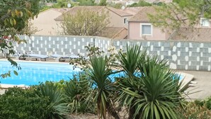A swimming pool surrounded by lush greenery and a tiled wall. - Quiet, independent studio between pine forest and sea. (Nissan-lez-Enserune)