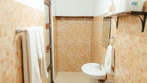 A bathroom with a tiled shower wall, a sink, and a towel rack. - Hotel Plaza Los Tucanes (Nuevo Santiago)