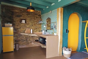 A kitchen with a stone wall, a yellow refrigerator, a sink, and a wooden counter. - Kalliberry Cycladic hidden gem with outdoor bathtub & amazing sunsets (Andros)