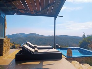 Ein Pool mit Liegestühlen, einer Pergola und Blick auf ferne Berge.