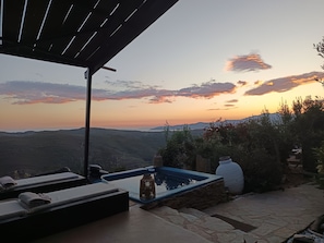 A terrace with a view of the landscape, a stone wall, and a small water feature. - Kalliberry Cycladic hidden gem with outdoor bathtub & amazing sunsets (Andros)