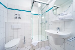 A modern bathroom with a glass-enclosed shower, a white sink, and a toilet. - Welcome to “Meeresbrise” – your cozy attic apartment with Baltic Sea charm. (Ostseebad Binz)