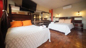 Une chambre d’hôtel avec deux lits, une télévision, un miroir, un bureau et un téléphone.