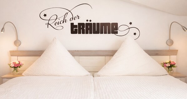 Un dormitorio con cama, dos mesitas de noche con lámparas y un adorno en la pared.