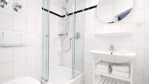 Un bagno moderno con doccia vetrata, lavabo bianco e specchio.