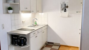 Una cucina compatta con lavello, due pensili, un piano di lavoro e una macchina da caffè.