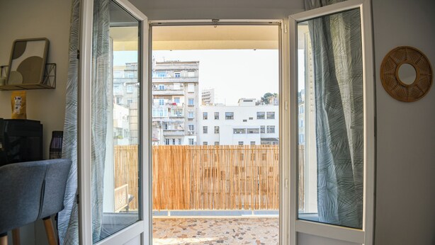 Ein offener Balkon mit Blick auf Gebäude und einen Holzzaun.