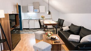 Eine moderne Wohnung mit Essbereich, Küchenzeile und einem Wohnzimmer mit Sofa und Hocker.