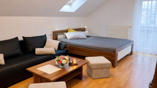 Ein modernes Schlafzimmer mit Schlafplatz in erhöhter Position, einer Couch, einem Couchtisch und einem kleinen Hocker.