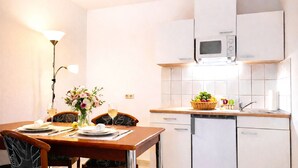 A compact kitchen with white cabinets, a microwave, and a fruit basket on the counter. - Welcome to “Donnerkeil” – your cozy seaside hideaway. (Ostseebad Binz)