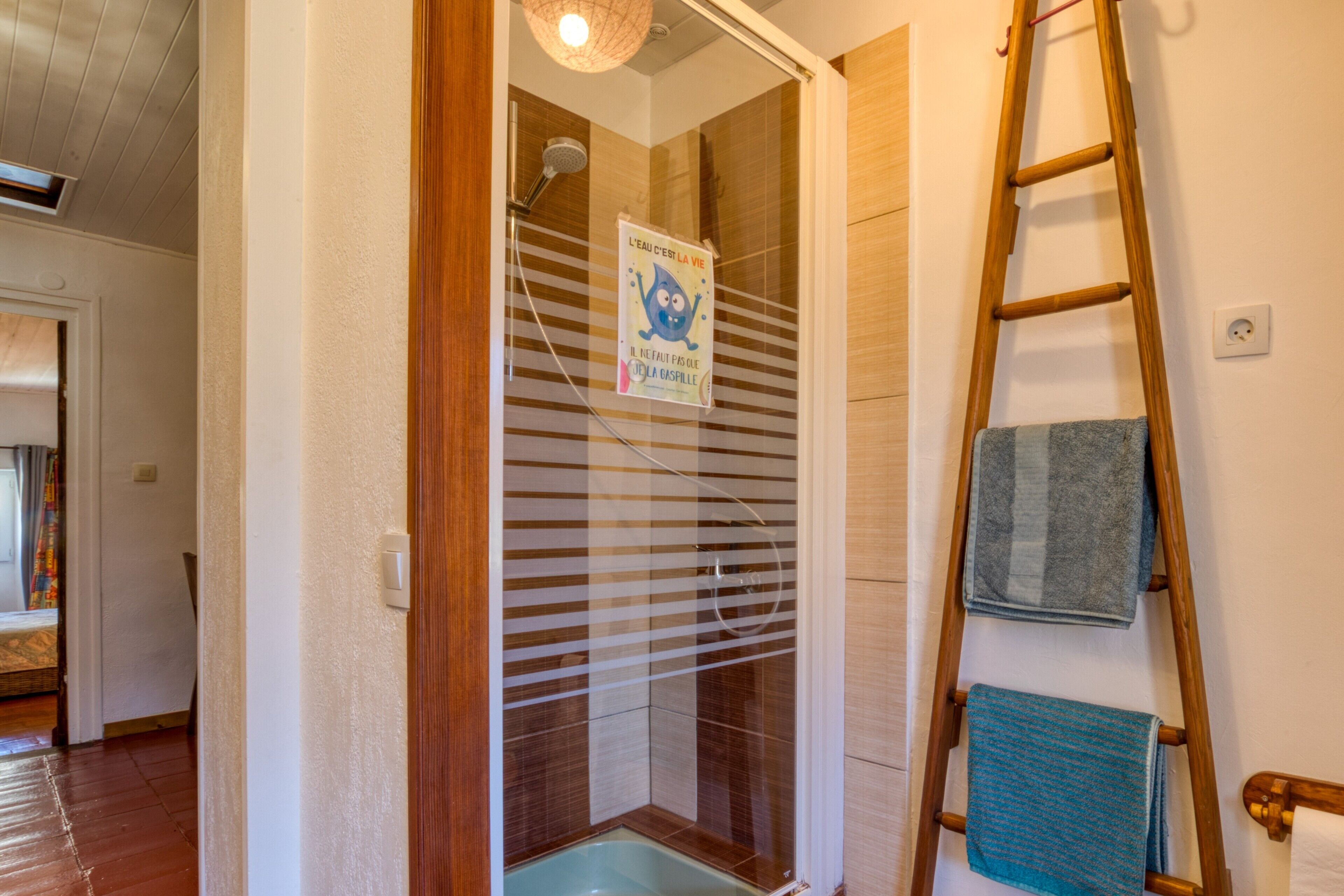 Ein Badezimmer mit Dusche, Handtuchhalter und einer Holzleiter.