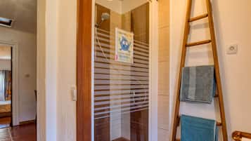 Ein Badezimmer mit Dusche, Handtuchhalter und einer Holzleiter.