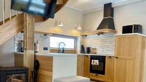 Una cocina moderna con escalera de madera, televisión empotrada y comedor con mesa redonda.