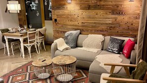 Una sala de estar acogedora con una pared de madera, una mesa redonda de centro, un sofá y un tapete estampado.